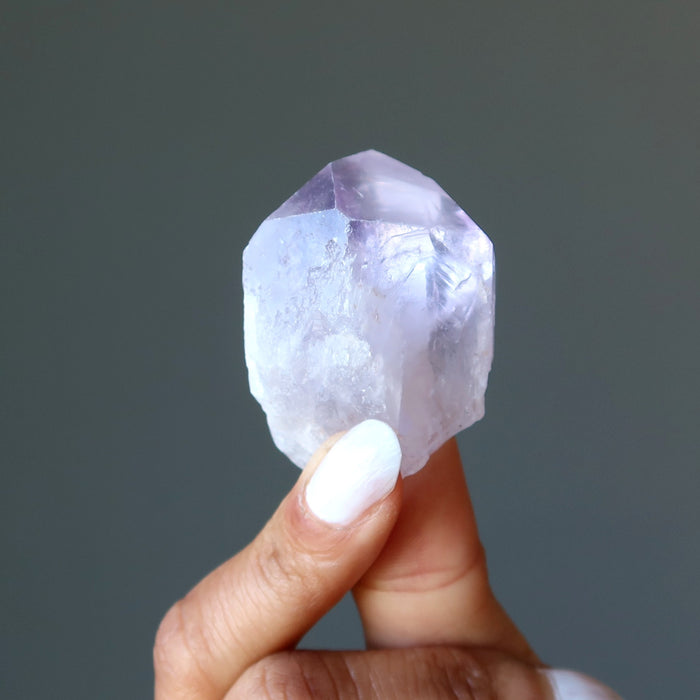 fingers holding a raw purple amethyst points