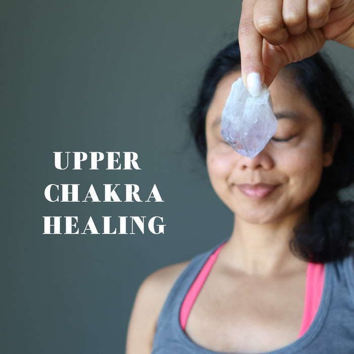 with eye closed sheila of satin crystals holding a raw purple amethyst point 