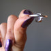 holding a faceted oval amethyst gemstone in silver ring