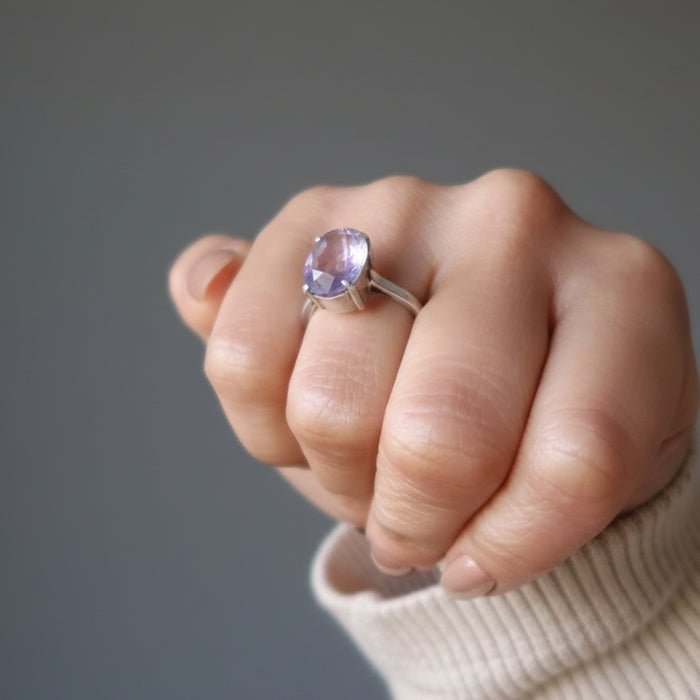 model wearing a faceted oval amethyst gemstone in silver ring