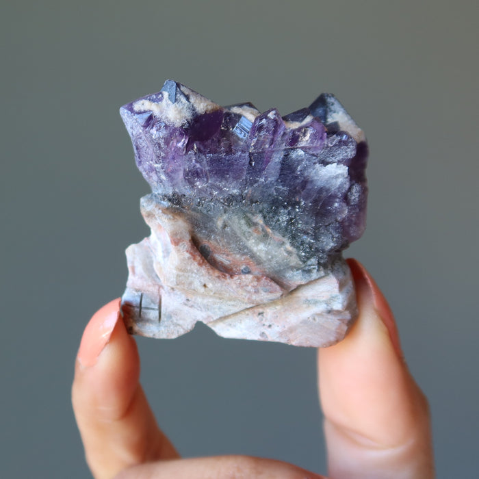 hand holding skull carved from an amethyst geode