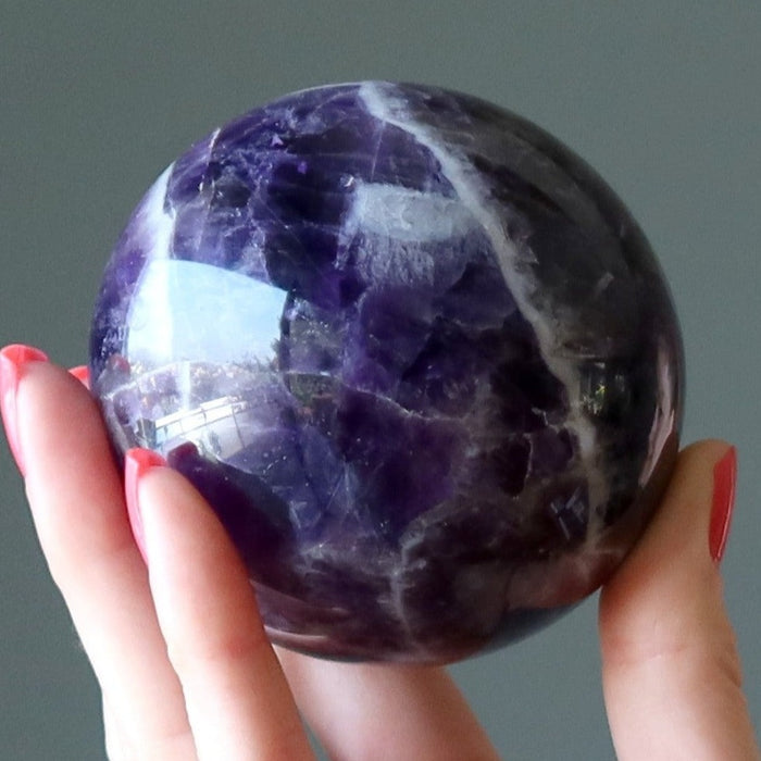 hand holding up a chevron amethyst sphere