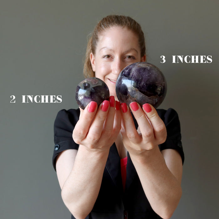 jamie of satin crystals holding two hand holding amethyst mineral mania spheres to show size difference