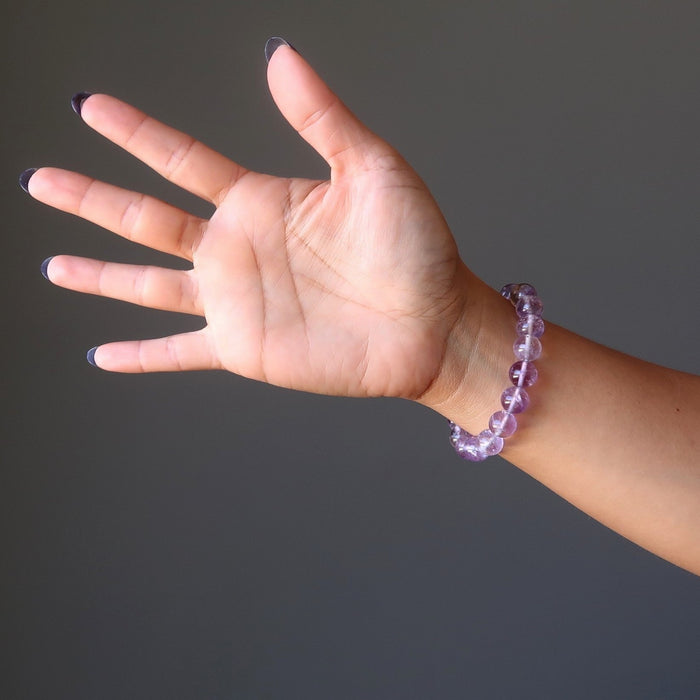 A woman's hand outstretched to show a round beaded purple ametrine crystal bracelet on her wrist