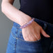 a woman with her hand in her blue jeans pocket showcases the ametrine bracelet on her wrist