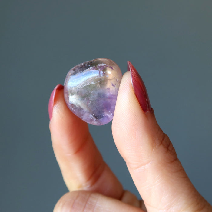 fingers holding amethyst citrine tumbled stone