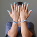 sheila of satin crystals with hands in front of face modeling angelite brass bracelets