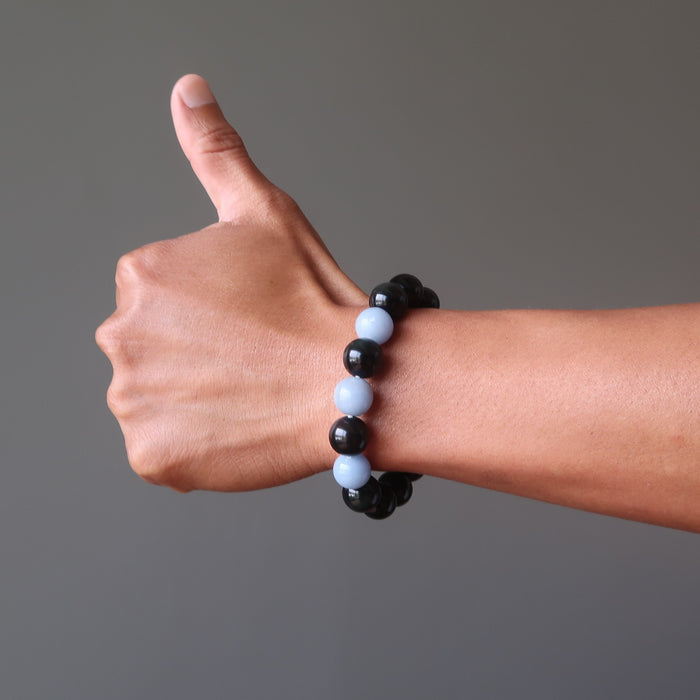 man's hand modeling blue angelite and black rainbow obsidian stretch bracelet