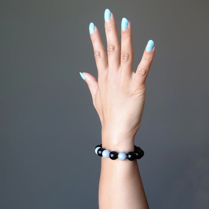 female hand modeling blue angelite and black rainbow obsidian stretch bracelet