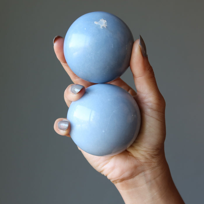 hand holding two angelite spheres