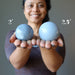 sheila of satin crystals holding out a 2" and a 2.5" angelite sphere