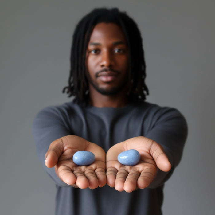 woman holding two angelite tumbled stones