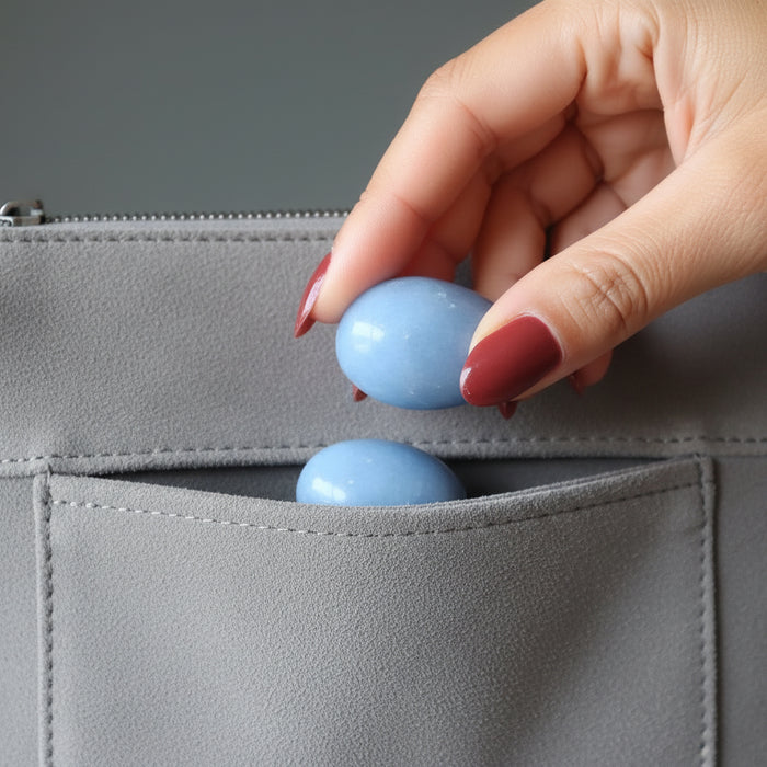 hand holding two angelite tumbled stones