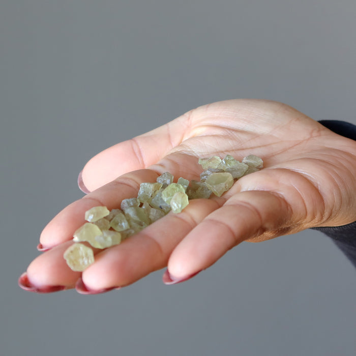 many raw green apatite stones on the palm