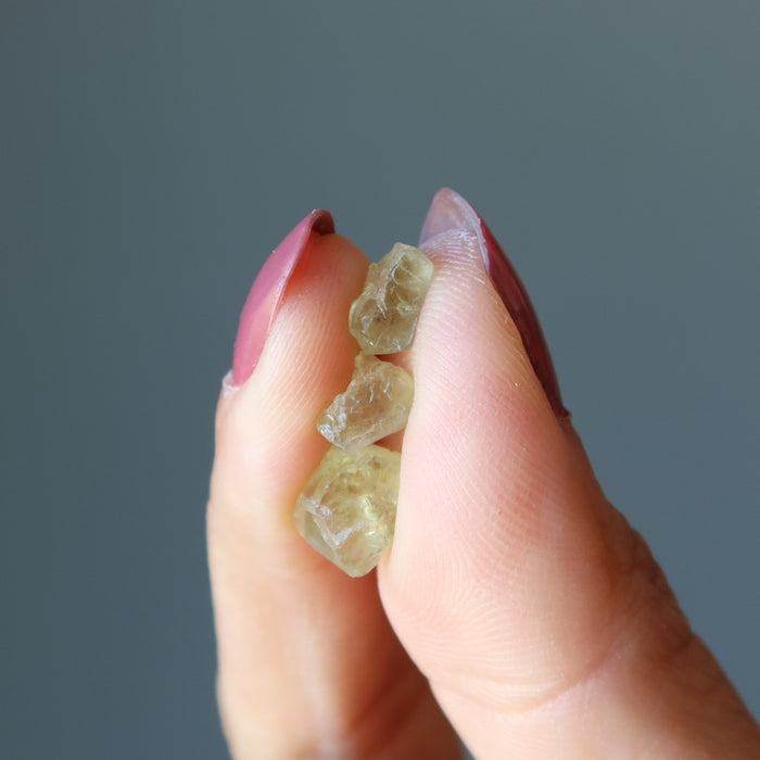 fingers holding three aw green apatite stones