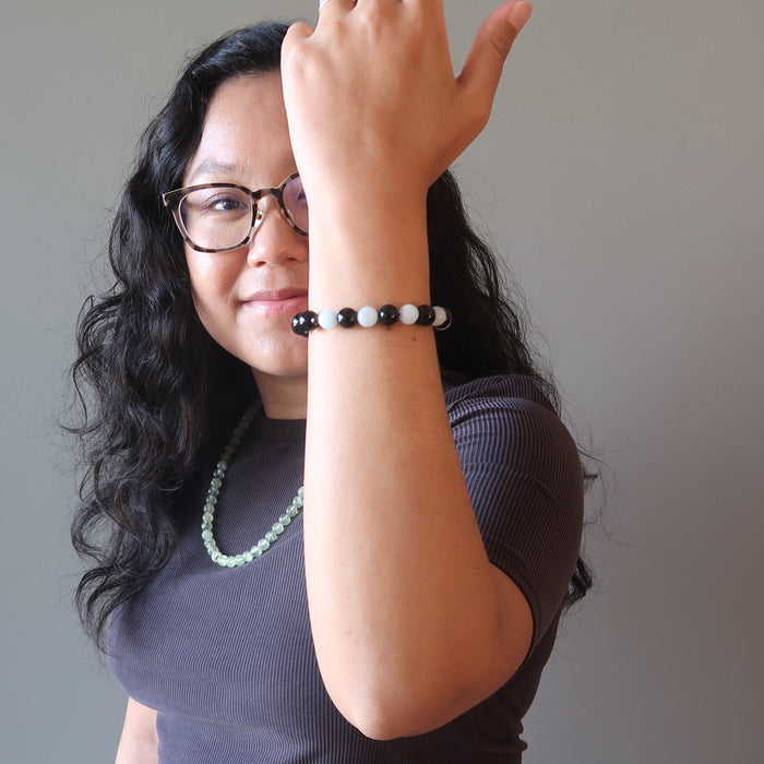 jessica of satin crystals with arm up wearing blue aquamarine and black rainbow obsidian stretch bracelet