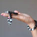 hand holding and wearing blue aquamarine and black rainbow obsidian stretch bracelets