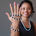 sheila of satin crystals holding up blue aquamarine and black rainbow obsidian stretch bracelets
