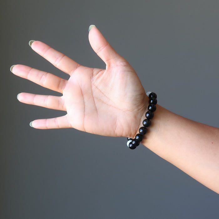 woman's hand out wearing blue aquamarine and black rainbow obsidian stretch bracelet