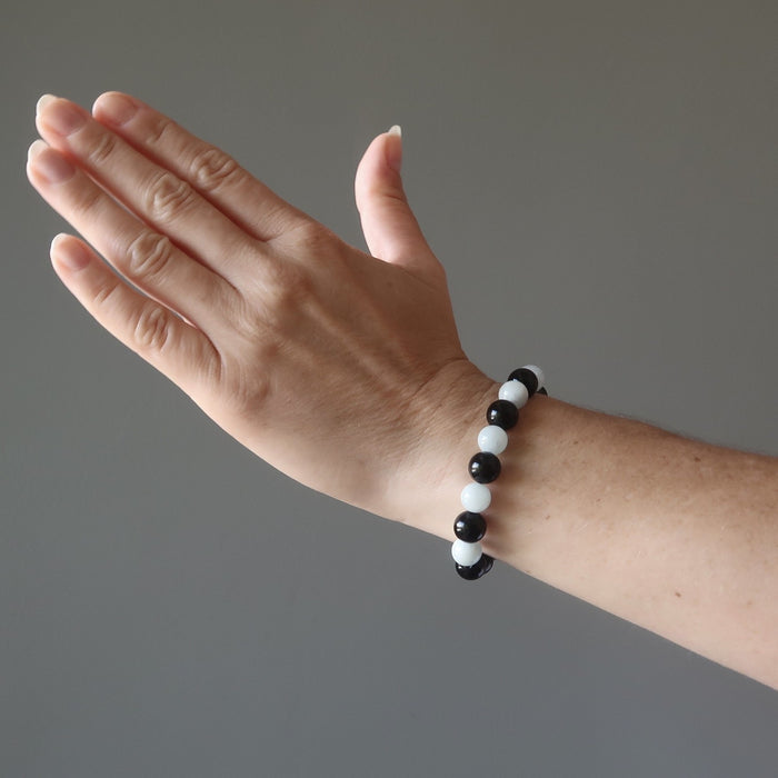 woman's hand modeling blue aquamarine and black rainbow obsidian stretch bracelet