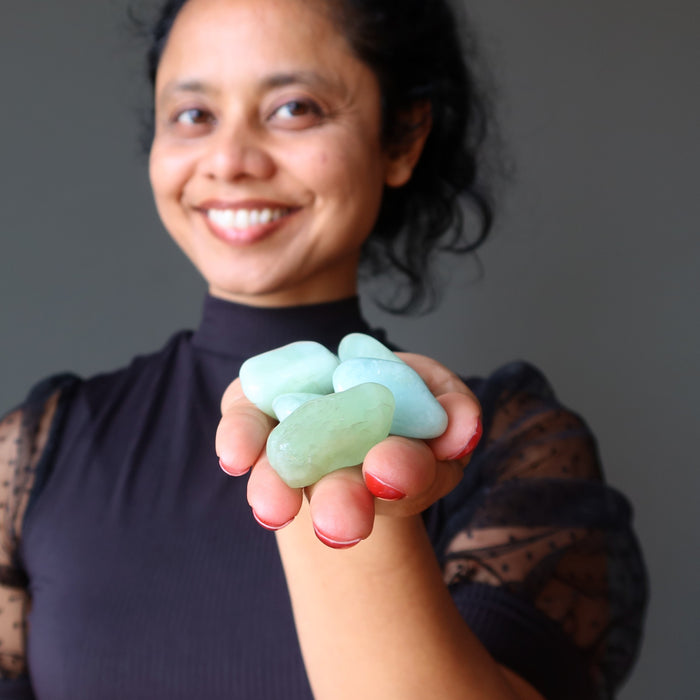 hand holding aquamarine tumbled stones