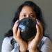 sheila of satin crystals holding an arfvedsonite sphere