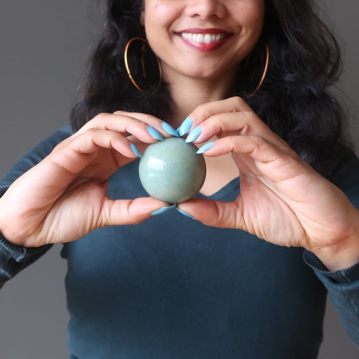 holding a green aventurine crystal ball