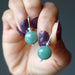 hand holding green aventurine circles in sterling silver earrings