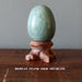 green aventurine egg on wood display stand
