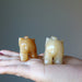 displaying back of two Golden Aventurine Elephant Figurines on model palm