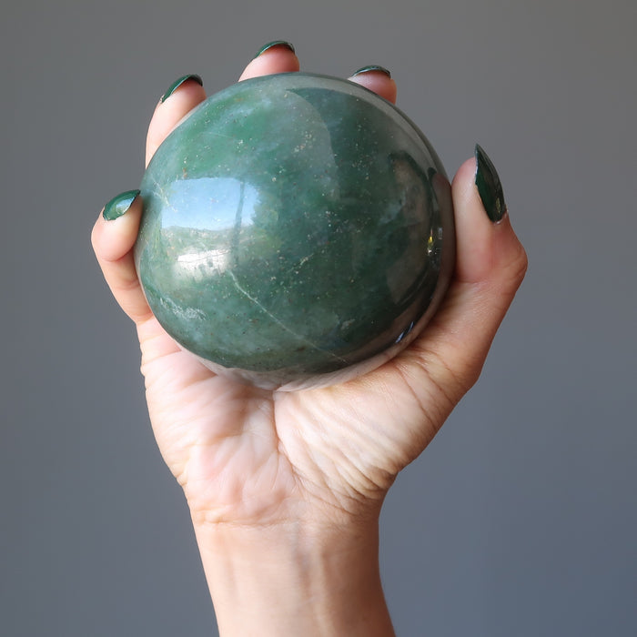 hand holding green aventurine sphere