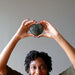 woman holding dark green aventurine hearts over head