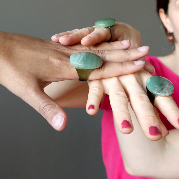 three hands wearing big green aventurine oval adjustable rings