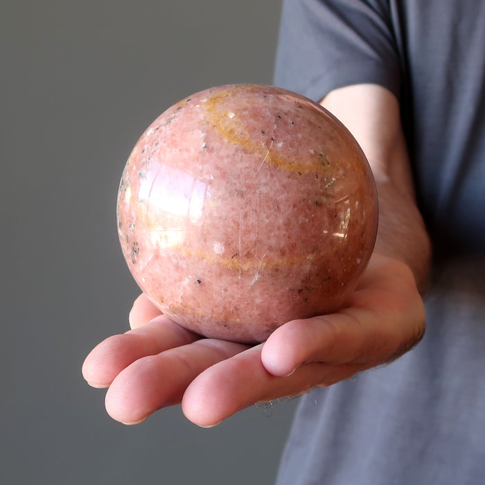 man hand holding pink aventurine ball