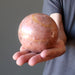 man hand holding pink aventurine ball