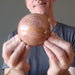 male holding pink aventurine sphere