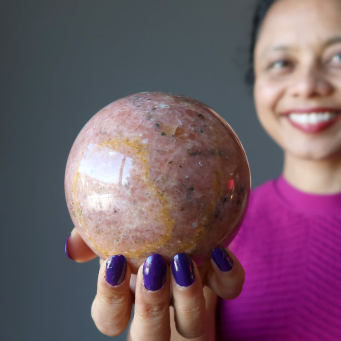 hand holding pink aventurine sphere