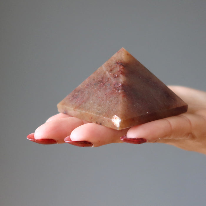 hand holding red aventurine pyramid