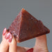 hand holding red aventurine pyramid