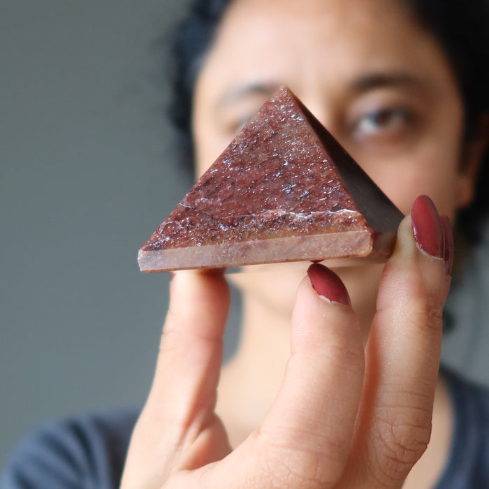 female holding red aventurine pyramid