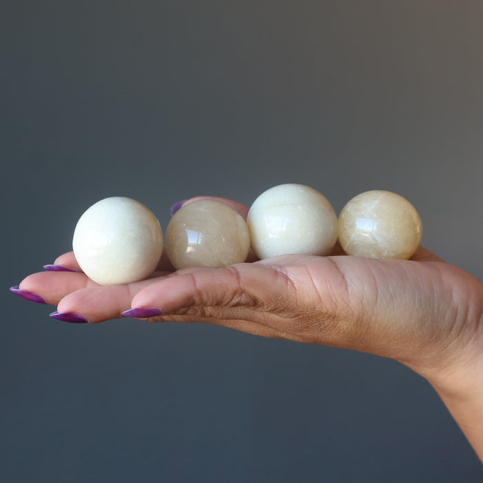 hand holding four aventurine spheres