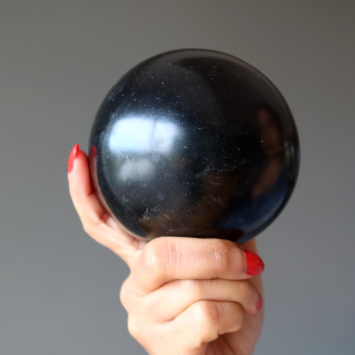 hand holding a black basalt sphere