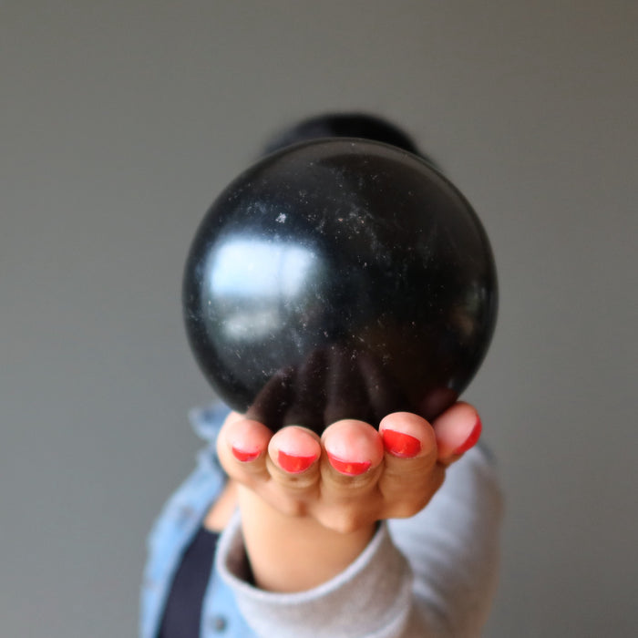 sheila of satin crystals holding a black basalt sphere