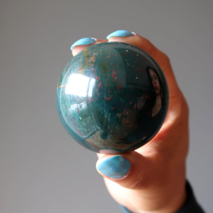 hand holding an indian bloodstone sphere