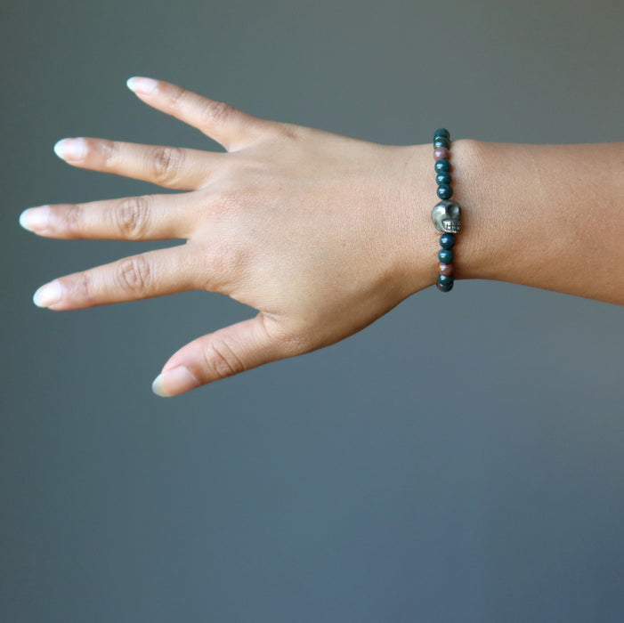 female hand wearing pyrite skull and round bloodstone beaded stretch bracelet