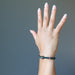 female hand wearing pyrite skull and round bloodstone beaded stretch bracelet
