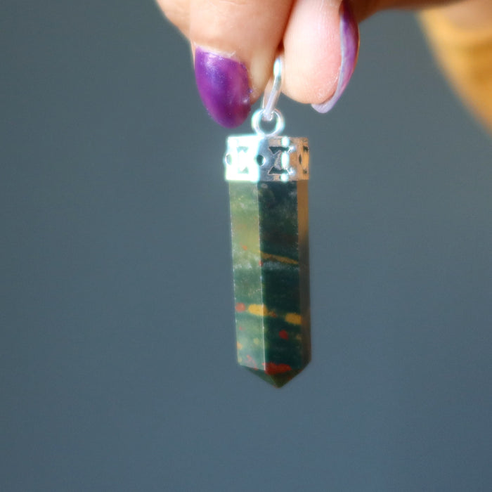 hand holding red and green bloodstone point pendant in silver 