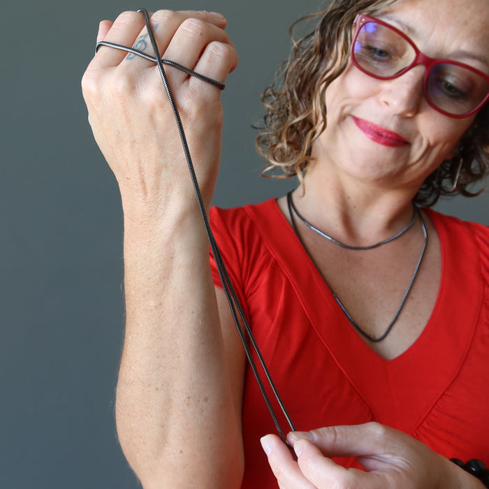 female model wearing gunmetal snake chain necklaces