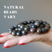 hand holding a pile of bronzite bracelets to show natural beads vary