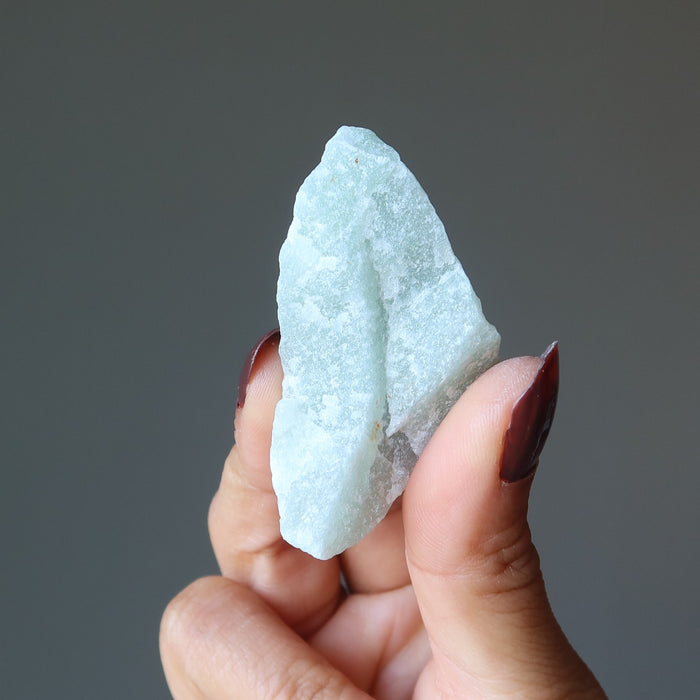 hand holding raw green calcite stone